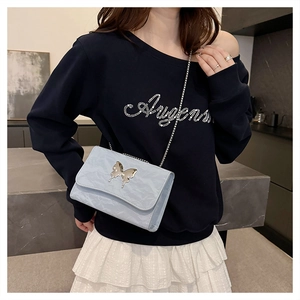 Detail of light blue pleated leather shoulder bag with silver butterfly buckle and chain