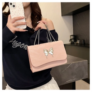 Close-up of pink satin shoulder bag with silver butterfly charm and metal chain strap