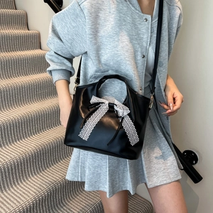 Bolso de mano negro minimalista con lazo de encaje blanco usado por modelo en escaleras