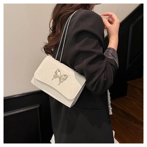 Detail of crossbody chain bag with marble texture and silver butterfly buckle on model