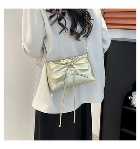 Detail view of a metallic gold crossbody bag with a large bow and elegant chain strap