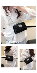 Close-up of black velvet crossbody bag featuring a large silver butterfly metal buckle