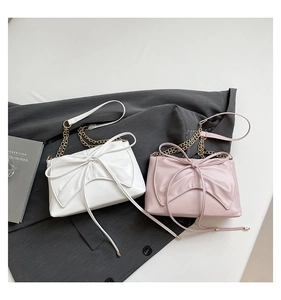 Detail of elegant PU leather shoulder bags in pearl white and pink with bow design