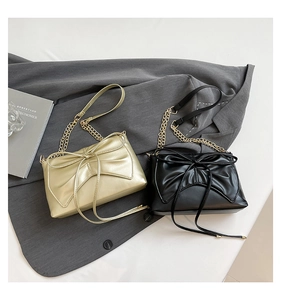 Detail of elegant bow designs and gold chains on black and champagne small square bags