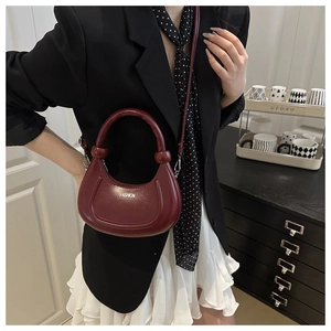 Détail du sac demi-lune bordeaux montrant l'imprimé mode et les accents de poignée boule