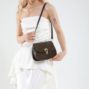 Sac bandoulière marron foncé motif serpent avec boucle dorée porté par un mannequin