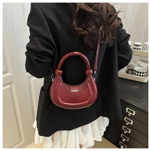 Détail d'un sac demi-lune bordeaux rétro avec poignée épaisse et lettrage fashion