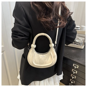 Detailed view of cream crescent crossbody bag with circular handle and FASHION lettering