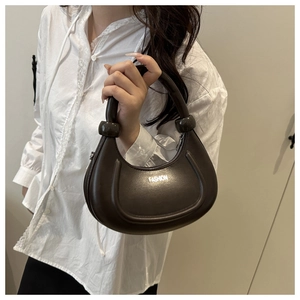 Détail du sac demi-lune marron foncé avec poignée nouée et imprimé mode sur le cuir