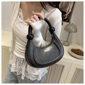 Détail d'un sac à main noir en demi-lune avec poignée nouée et imprimé mode chic