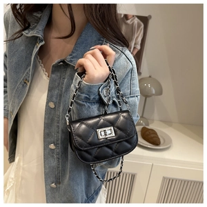 Close-up of a mini black quilted crossbody bag with silver clasp and chain strap detail
