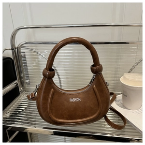 Détail du sac demi-lune marron avec logo argenté et texture en cuir PU lisse et élégant