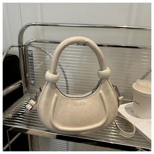 Détail du sac demi-lune crème avec poignée souple épaisse et lettrage fashion argenté