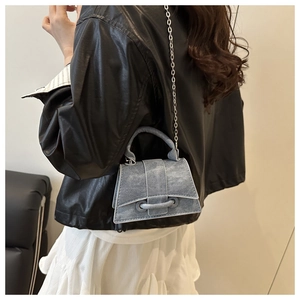 Mini trapezoid denim crossbody bag with silver chain strap shown on a model
