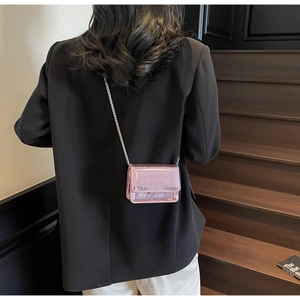 Close-up of a glossy pink crocodile texture mini flap bag with a sleek metal chain
