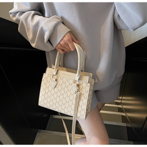Gros plan d'un sac cabas beige avec imprimé M marron et bandoulière amovible incluse