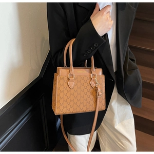 Détail du sac cabas marron à monogramme avec lettrage doré et poignées en cuir solides