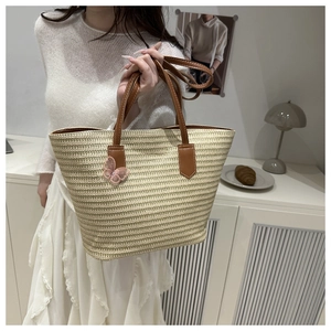 Détail du sac cabas en paille tissé main avec anses en cuir marron et nœud en dentelle