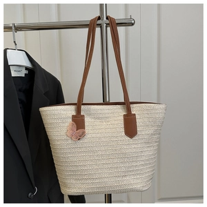 Détail du sac cabas en paille blanche avec nœud en tulle rose et anses en cuir brun