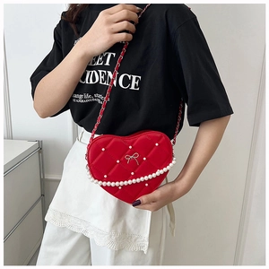 Detail of red heart-shaped crossbody bag with quilted pattern and pearl chain accent