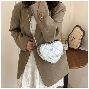 Detail of silver heart-shaped crossbody bag with quilted pattern and pearl chain strap
