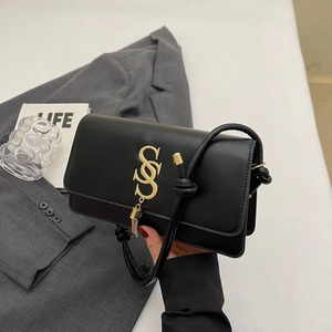 Minimalist black leather crossbody bag with gold logo, tassel detail and knotted strap