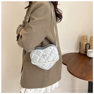 Detail of silver heart-shaped crossbody bag with quilted pattern and pearl chain
