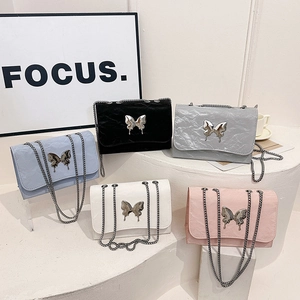Elegant butterfly chain underarm bags in five colors on a minimalist display