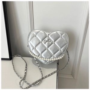Detail of silver heart-shaped quilted crossbody bag with pearl trim and bow accent