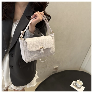 Detail of cream woven leather shoulder bag with gold metal buckle and sturdy flap cover