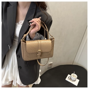 Detail shot of beige faux leather handbag with crocodile pattern and gold buckle