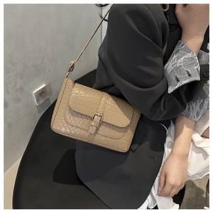 Close-up of retro woven pattern texture on beige crossbody bag with gold metal clasp