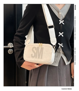 Detail of white suede square bag with rhinestone SM letters and wide fabric strap