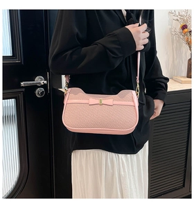 Borsa a tracolla rosa con fiocco e trama intrecciata indossata da modella con gonna bianca