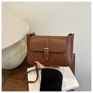 Close-up of brown woven texture and vintage gold buckle on a stylish square shoulder bag