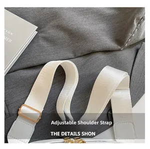 Detailed view of the white adjustable nylon shoulder strap with gold metal buckle