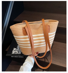 Détail du sac cabas en paille tissée avec rayures blanches et anses en cuir marron