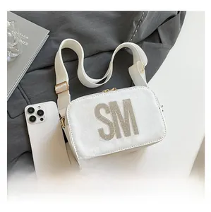 White leather camera bag with sparkling SM rhinestone logo and wide canvas strap