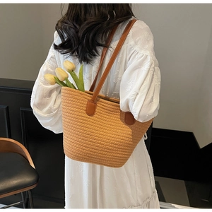 Détail du sac cabas tissé avec anses en cuir porté avec une robe blanche texturée