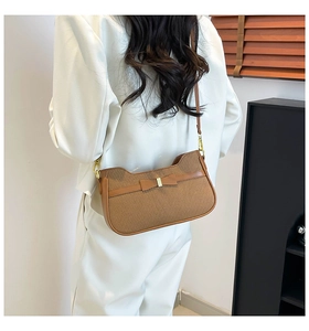 Detailed shot of retro brown underarm bag with bow detail on white blazer