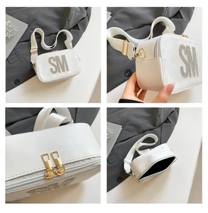 Detail view of white camera bag with rhinestone SM logo and wide fabric strap