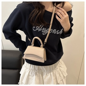 Litchi texture beige handbag detail shown on model with shoulder strap and gold hardware