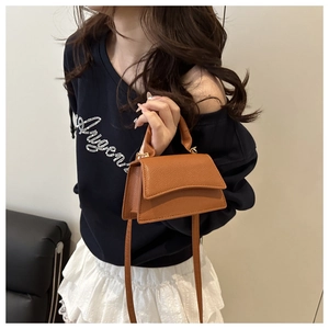 Close-up of brown litchi pattern leather handbag with top handle and crossbody strap