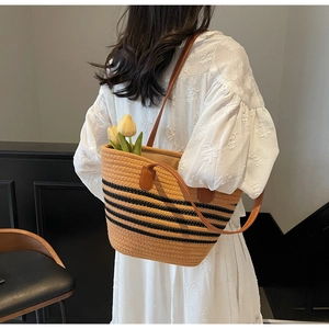 Détail du sac cabas en paille tissée avec rayures noires et lanières en cuir marron