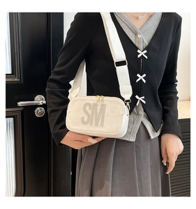 Detailed view of white crossbody bag with silver rhinestone SM logo and wide strap