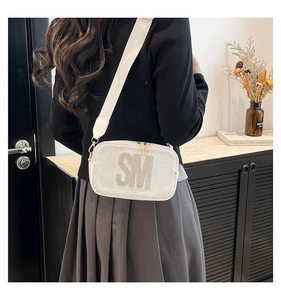 Detailed view of a white crossbody bag featuring rhinestone-encrusted SM logo and wide strap
