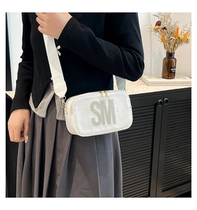 White crossbody bag with rhinestone letters and a wide canvas strap on model