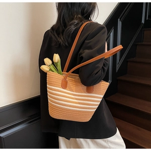 Détail du sac cabas tissé avec rayures blanches et lanières en cuir porté par un mannequin