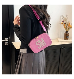 Detail of pink suede crossbody bag featuring rhinestone SM initials and wide strap