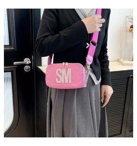 Detail view of pink rectangular crossbody bag with rhinestone SM initials and wide strap